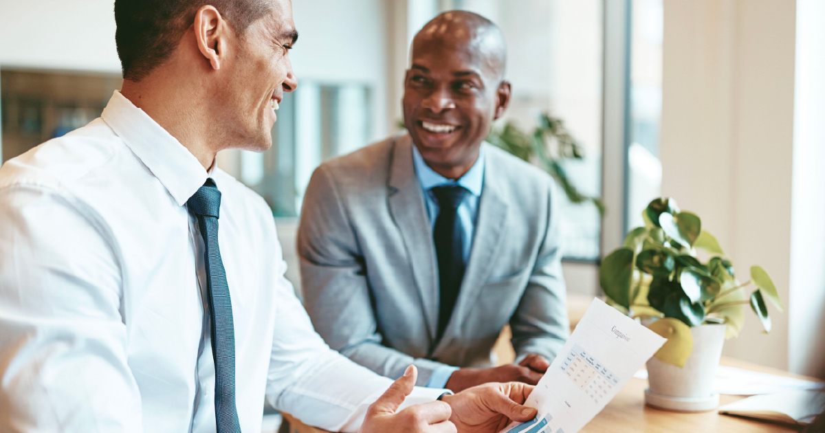 Two people smile while practicing sales techniques